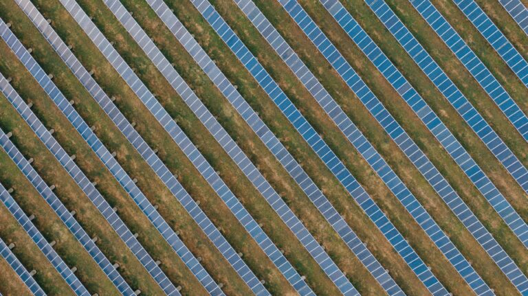 Aerial view of uniform solar panels in a green field, showcasing sustainable energy.