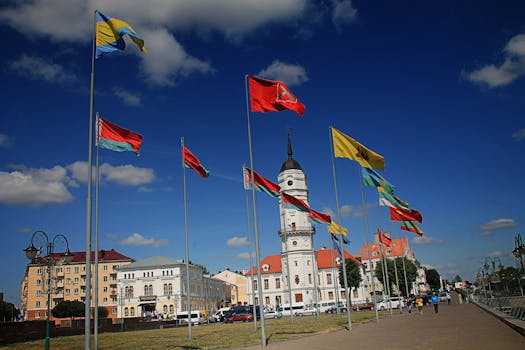 Flags waving near the city hall in Mahilioŭ, Belarus against a deep blue sky.
